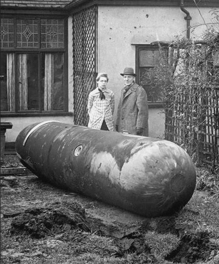 Homeowners stand next to a large bomb next to their home.