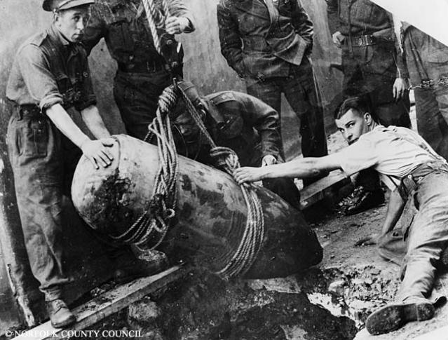 British soldiers raise an unexploded bomb from the ground.